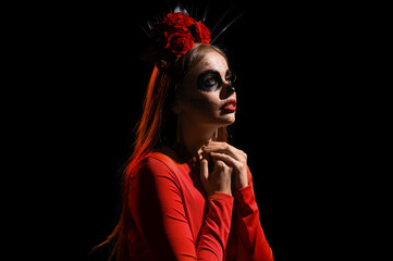 Young woman with painted skull on her face against black background. Celebration of Mexico's Day of the Dead (El Dia de Muertos)