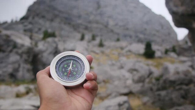 hand with compass and out of focus a family that is taking an excursion through a national park. Concept of family time in nature and national park. Finding the way, teamwork and solution orientation.