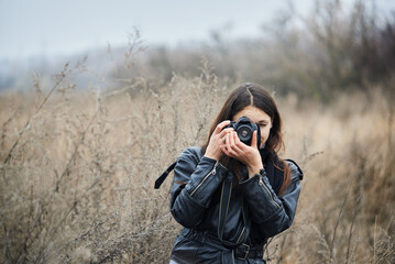 Portrait of a photographer taking pictures of nature against the backdrop of an autumn field.