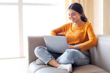 Obraz premium Smiling young indian freelancer woman with laptop working from home