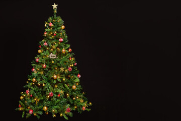 Beautifully decorated and illuminated Christmas tree on a black background. Xmas decoration and illumination concept.