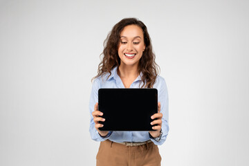 Positive european young woman professional show tablet with empty space
