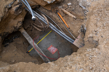 Underground electric cable infrastructure communication installation at a construction site with various cables protected in tubes. High-speed internet network cables are buried underground