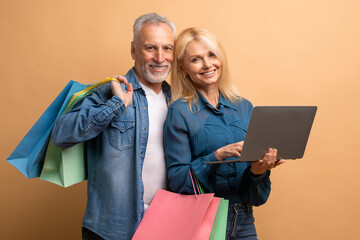 Cheerful elderly man and woman shopping on Internet, using laptop