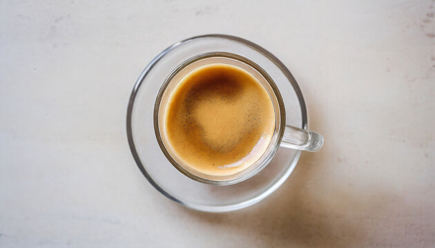 A glass of espresso on light colour table top. Close up overhead view.