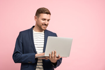 Friendly smiling unshaved man holding laptop, having video call, good idea, problem solution. Stylish optimistic positive man looks like manager, marketer, ceo, executive working in modern office