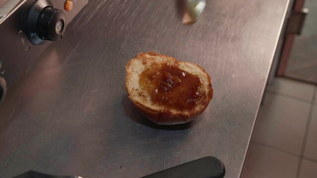 Chef in black gloves making burge. spread sauce on bun. Close-up of a skilled craftsman working at the workplace 