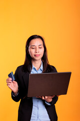 Filipino woman using credit card to do online shopping, buying stylish clothes using laptop...