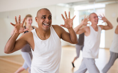 Portrait of cheerful male dancer during group dance workout in fitness center - obrazy, fototapety, plakaty