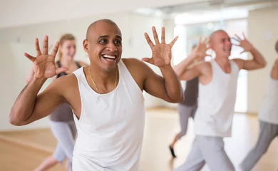 Fototapeten Portrait of cheerful male dancer during group dance workout in fitness center © JackF