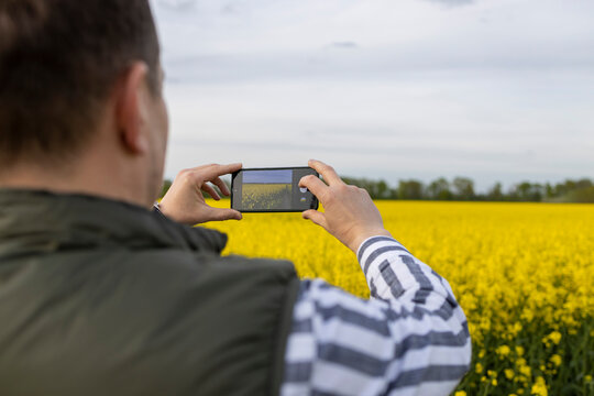 Mature man capturing nature's bloom through smartphone lens.