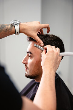 Barber cutting a client's hair with a razor.
