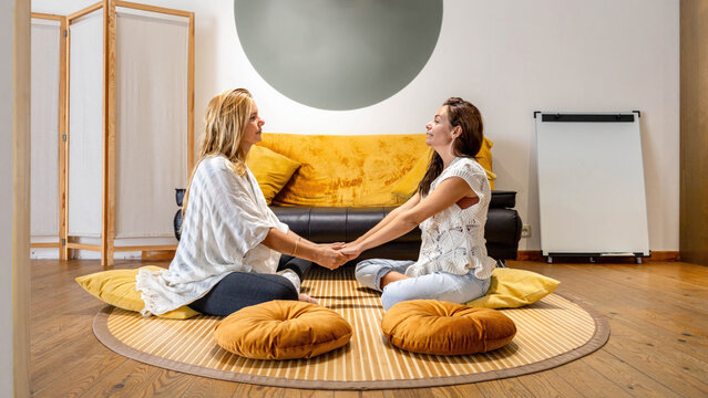 A woman sitting on the floor talking to another woman - Powered by Adobe