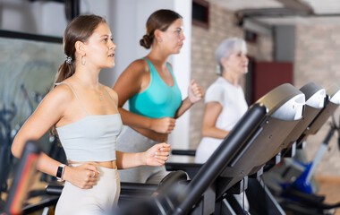 Fototapeta premium Sporty woman doing cardio workout running on treadmill at fitness center