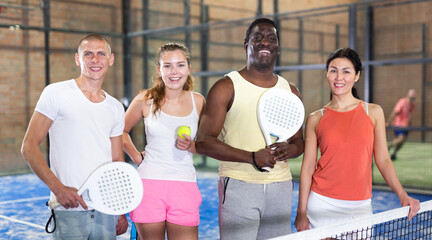 Group portrait of team of padel players standing at tennis court at fitness health club