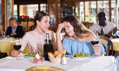 Portrait of two young women friends or lgbt couple having problems in relations, arguing in restaurant