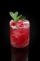 Fresh ice cold berry juice drink with mint, summer raspberry lemonade in a glass on a dark background with reflection