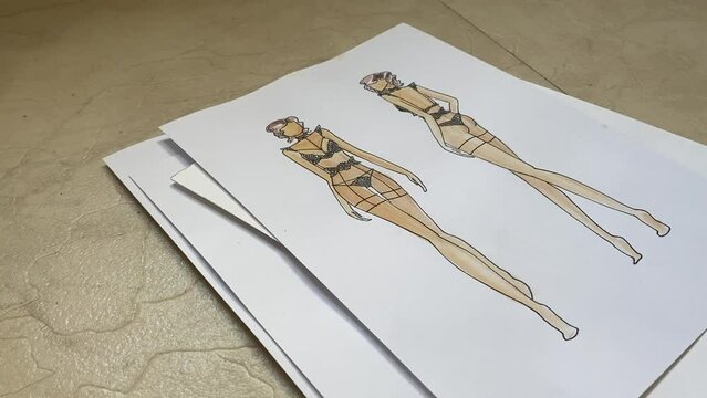 Woman looking at sketches of underwear. 