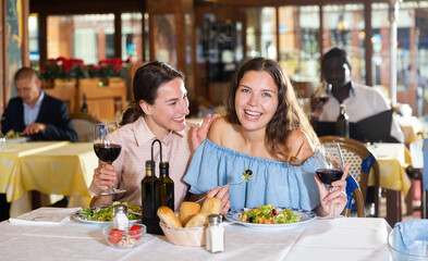 Two best friends have fun talking at a table in a restaurant