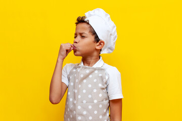 little chef child african american in uniform shows italian taste gesture on yellow isolated...