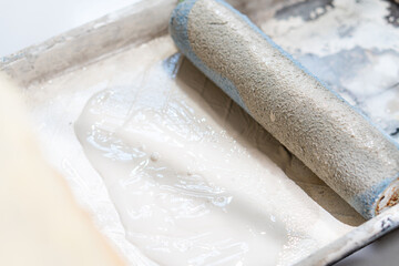 Male hand painting wall with paint roller.