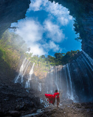 Tumpak Sewu in East Java, Indonesia with young woman in red dress