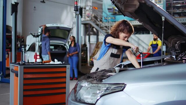 Qualified engineer in repair shop using torque wrench to tighten screws after opening car to check its parameters during maintenance. Expert using professional tool in garage to mend busted vehicle