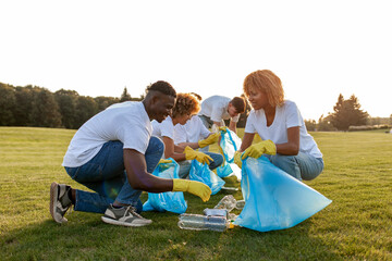 multiracial group of people volunteers with garbage bags collecting garbage and plastic in the park