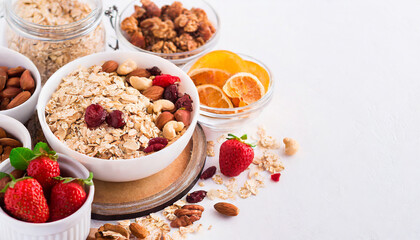 Muesli bowl, organic ingredients for healthy breakfast Granola, nuts, dried fruits, oatmeal, whole grain flakes on white background. Copy space