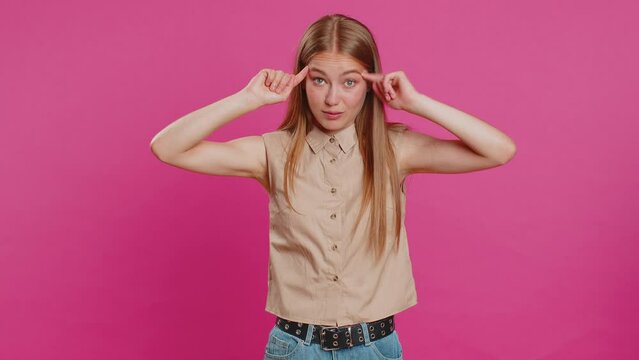 You are crazy, out of mind. Displeased woman pointing at camera, show stupid gesture finger near head, blaming some idiot for dumb insane plan idea, senseless talk. Girl isolated on pink background