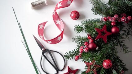 Festive video of Christmas wreath making with your own hands. Decor and decoration for the house, fir branches, stars,cones, wire and scissors lying on the table, view from above.Christmas floristics.