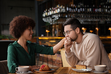 Fototapeta na wymiar International relationships. Handsome man kissing her girlfriend's hand in cafe