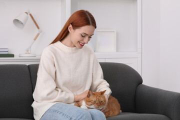 Happy woman with her cute cat on sofa at home