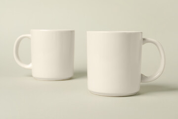 Two white ceramic mugs on light grey background