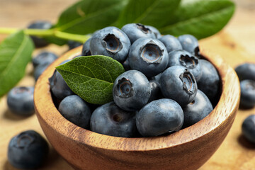 Bowl of fresh tasty blueberries on table, closeup