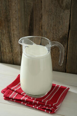Jug of fresh milk on white wooden table