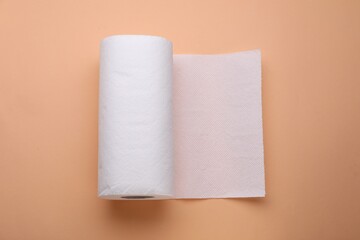 Roll of tissue towels on beige background, top view