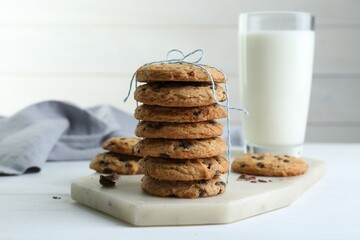 Tasty chocolate chip cookies and glass of milk on white wooden table, closeup
