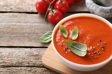 Delicious tomato soup on wooden table, space for text