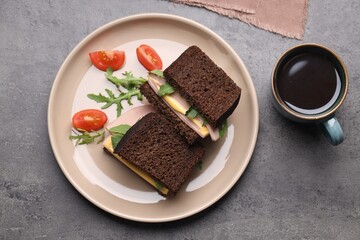 Delicious sandwiches with boiled sausage, tomato, cheese and arugula on grey table, flat lay