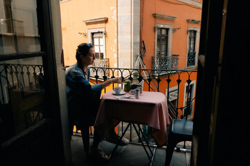 a girl has breakfast in a cafe on the balcony overlooking the street. Mexico