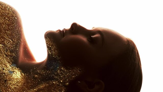 Vertical video. Spiritual enlightenment. Soul beauty. Double exposure art profile portrait of woman with abstract gold glitter ink flow motion isolated on white background.
