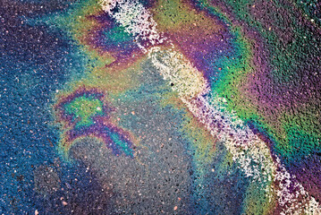 Oil spill on wet asphalt, parking lot with dividing line
