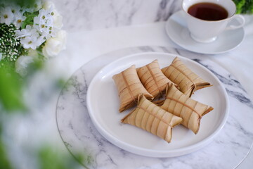 Lepet or Leupeut is a type of snack made from glutinous rice mixed with peanuts, cooked in coconut milk, then wrapped in coconut leaves. Close up view