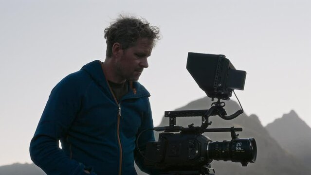 Filmmaker In Blue Jacket Using A Camera