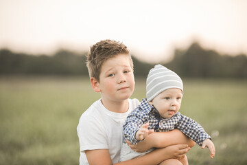 Cute boys  outside, older brother hugs younger, taking care of sibling. Concept siblings and candid...