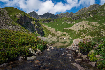 View of the Dukka lake "Rybka" and the Malaya Dukka River on the slopes of the Arkasar ridge in the North Caucasus on a sunny summer day, Arkhyz, Karachay-Cherkessia, Russia © Ula Ulachka