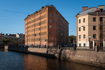 Naklejka premium View of a residential building in the shape of an iron on the embankment of the Griboyedov Canal on a sunny day, St. Petersburg, Russia