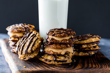 Many chocolate and caramel lace cookie sandwiches, served with milk.