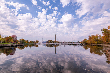 Fototapeta premium blue sky and puffy white clouds reflected in the yacht basin at ashbridges bay in toronto with the downtown city skyline in the background 